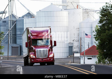 Un rosso carrello commerciale la guida passato elevatori della granella nel paese di fattoria di Eastern Washington, Stati Uniti d'America. Foto Stock