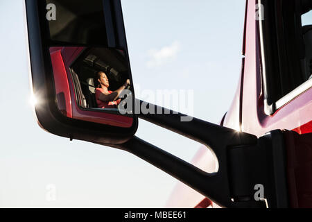 Vista di una donna caucasica conducente nella cabina del suo camion commerciali. Foto Stock