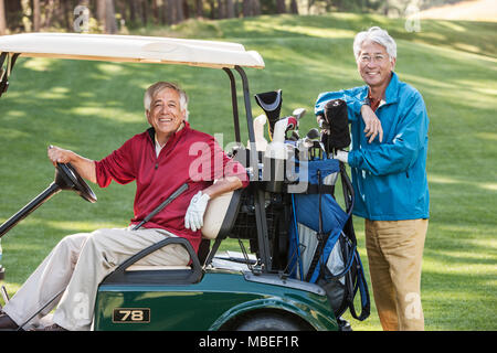 Due anziani di sesso maschile gli amici del golf e il loro carrello da golf e club. Foto Stock