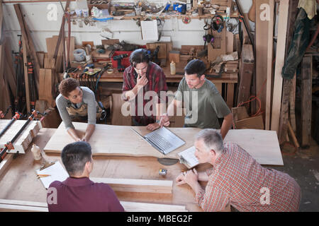 Un team di multi-razziale lavoratori in fabbrica problem solving in corrispondenza di una stazione di lavoro in una fabbrica per la lavorazione del legno. Foto Stock