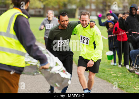 Runner aiutando uomo ferito in esecuzione a maratona Foto Stock