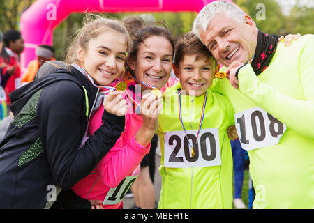 Ritratto sorridente, fiduciosi family guide di scorrimento che mostra le medaglie alla carità eseguire Foto Stock