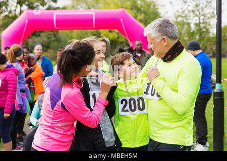 La famiglia felice con le medaglie della carità di finitura run, celebrando Foto Stock