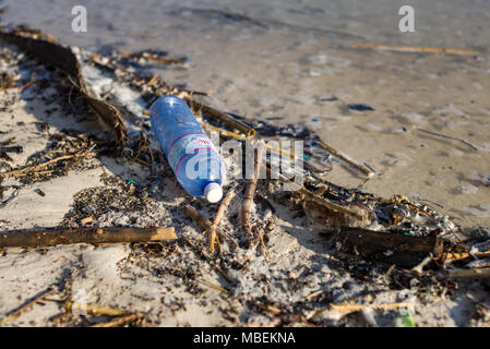 La bottiglia di plastica rifiuti giace lavato fino sulla riva di una spiaggia di sabbia bianca Foto Stock