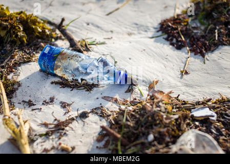 La bottiglia di plastica rifiuti giace lavato fino sulla riva di una spiaggia di sabbia bianca Foto Stock