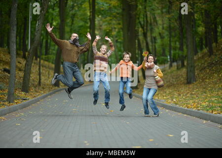 Famiglia nella foresta di autunno jumping Foto Stock