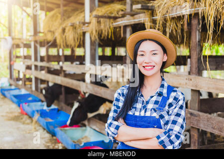 Felice asia agricoltore in posa di una stalla Foto Stock