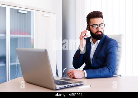 Giovane avvocato parlando al telefono mentre si lavora sul computer portatile Foto Stock
