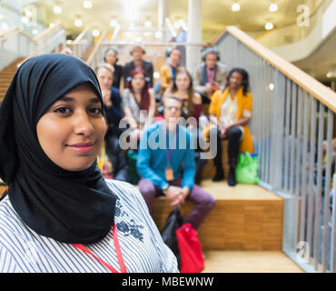 Ritratto femminile fiducioso altoparlante in hijab con il pubblico in background Foto Stock