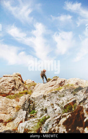 Rocciatore raggiungendo il top delle rocce Foto Stock