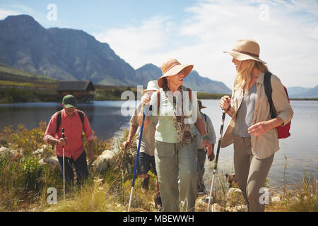 Attiva le donne senior amici escursionismo lungo la soleggiata estate lago Foto Stock