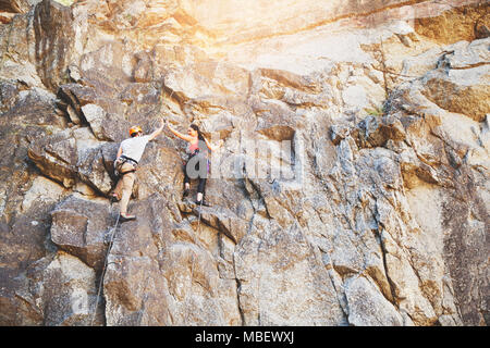 Arrampicatori ad alta fiving sulla parete di roccia Foto Stock