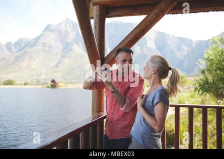 Coppia felice con il binocolo godendo di vista lago dal balcone Foto Stock