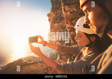 Arrampicatori con la fotocamera del telefono a fotografare vista oceano Foto Stock