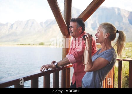 Giovane con un binocolo godendo di vista lago dal balcone Foto Stock