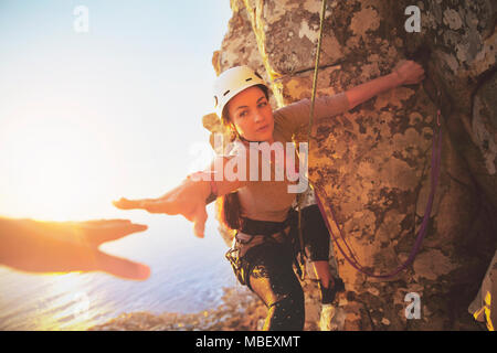 Femmina di rocciatore raggiungendo per la mano Foto Stock