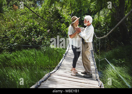 Attivo romantica coppia senior tenendo le mani sulla passerella idilliaco Foto Stock