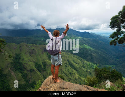 Giovane donna caucasica escursionista con zaino in piedi sulla cima della montagna e godersi la vista della valle di picco Ella Foto Stock