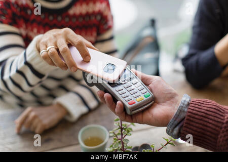 Donna con smart phone utilizzando il pagamento senza contatto Foto Stock