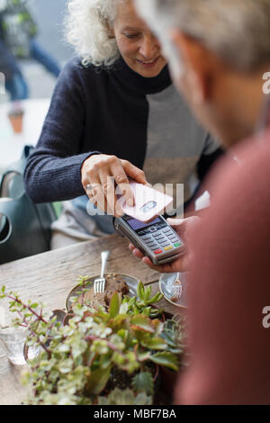 Donna con smart phone utilizzando il pagamento senza contatto Foto Stock