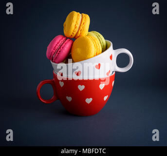 Multicolore di dolci da forno di farina di mandorle macarons in un bianco coppa in ceramica su sfondo nero Foto Stock