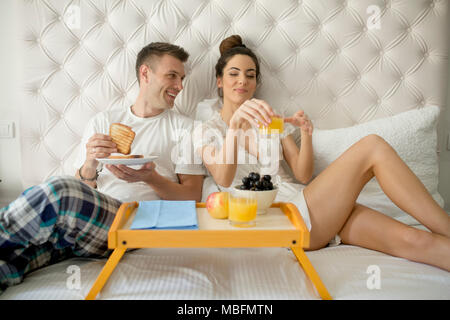 Giovane coppia felice avendo prima colazione in camera di lusso Foto Stock