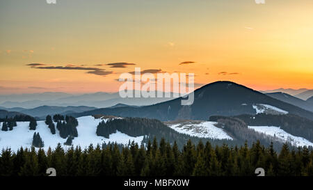 Sommeralm Stiria Austria visualizzare su un cielo arancione dopo il tramonto e le montagne con macchie di neve di primavera Foto Stock