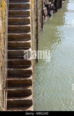 Una serie di gradini di pietra che conduce verso il basso a partire da un vecchio porto della Cornovaglia muro a St Ives in porto per accedere tot egli le barche e i pescherecci per la pesca a strascico in porto Foto Stock