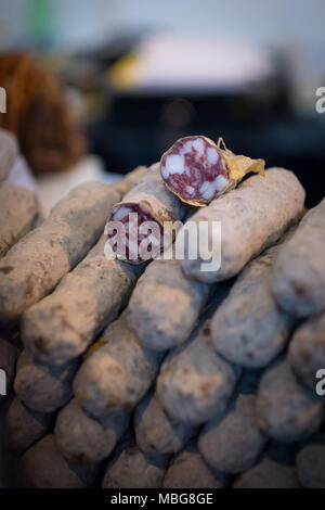 Pila di essiccato salame salsicce, vicino a un mercato con fette di quelli sulla parte superiore Foto Stock