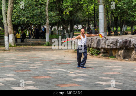 Un uomo cinese sguaina due spade come egli pratica le arti marziali in Yangshuo Park, Yangshuo, Cina. Foto Stock