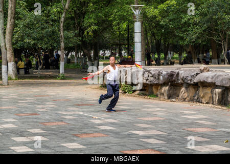 Un uomo cinese sguaina due spade come egli pratica le arti marziali in Yangshuo Park, Yangshuo, Cina. Foto Stock