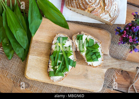 Due fette di pane di pasta acida con burro e aglio selvatico lascia Foto Stock