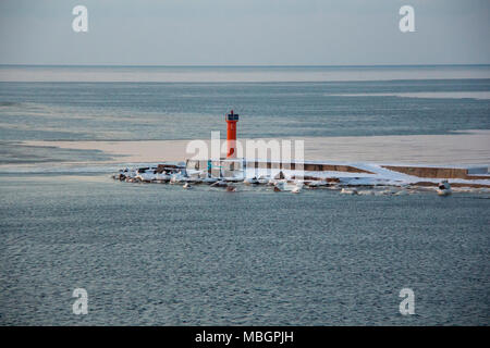 Faro rosso sulla diga frangiflutti in Riga Europe.promenade al rosso Mangalsala Faro, situato a Riga Porta a Mare, Lettonia.Inverno e mare frouzen in ghiaccio Foto Stock