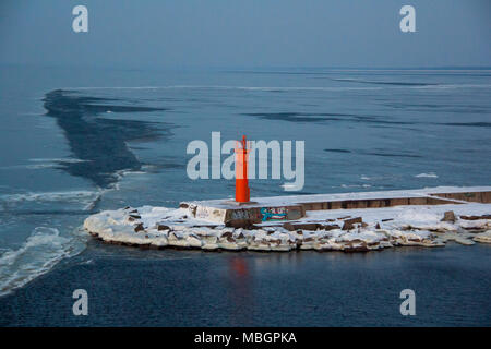 Faro rosso sulla diga frangiflutti in Riga Europe.promenade al rosso Mangalsala Faro, situato a Riga Porta a Mare, Lettonia.Inverno e mare frouzen in ghiaccio Foto Stock