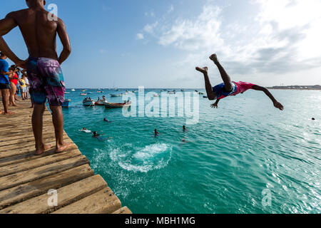 Ragazzo che salta da un molo in legno blu oceano in Santa Maria, Sal, Capo Verde, Cabo Verde Foto Stock