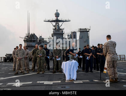 Stati Uniti 5TH FLOTTA AREA DI OPERAZIONI (1 aprile 2018) DEGLI STATI UNITI Navy Lt. La Cmdr. John M. Mabus, un cappellano della marina militare assegnato al XXVI Marine Expeditionary Unit, offre una Domenica di Pasqua i servizi sunrise sul ponte di volo dell'harpers Ferry-class dock landing ship USS Oak Hill (LSD 51). Oak Hill, home-ported a Virginia Beach, Virginia, è su un regolarmente la distribuzione programmata per gli Stati Uniti Quinta Flotta area di operazioni a sostegno della sicurezza marittima operazioni per rassicurare gli alleati e partner e preservare la libertà di navigazione e il libero flusso di commercio nella regione. Foto Stock