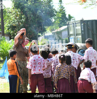 Indonesia (5 aprile 2018) Utilitiesman 2a classe Brenden Lewis, da Fredonia, Kan., attualmente assegnato alla Naval Mobile Battaglione di costruzione quattro (NMBC) 4, si prende una pausa dal lavoro di costruzione di dedicare qualche minuto a giocare con gli studenti di SB 83 elementari. NMBC 4 sta assistendo con conoscenze di ingegneria durante gli scambi di partenariato Pacifico 2018 (PP18). PP18's missione è lavorare collettivamente con host e nazioni partner per migliorare l'interoperabilità a livello regionale di emergenza e capacità di risposta, aumentare la stabilità e la sicurezza nella regione e favorire la nascita di nuove e durature amicizie attraverso la Foto Stock