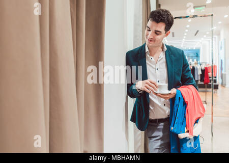 L uomo nel negozio di moda in attesa per la sua donna per apparire dalla sala di montaggio Foto Stock