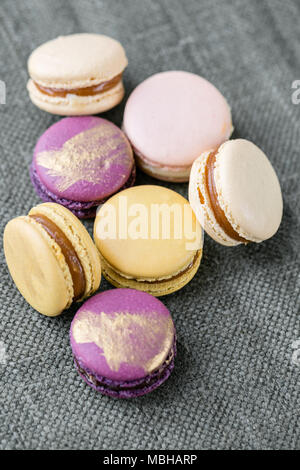 Close-up colorato in francese o in italiano di macaron su bianco tavolo in legno. Macaron è francese dessert servito con tè o caffè. sfondo, foto verticale Foto Stock