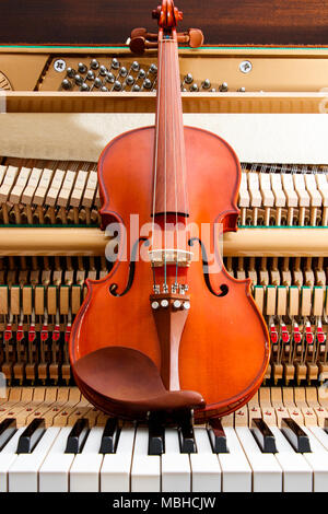 Marrone Classico violino sul vicino l immagine di i tasti del pianoforte e interno che mostra le stringhe, martello e la struttura dello sfondo Foto Stock