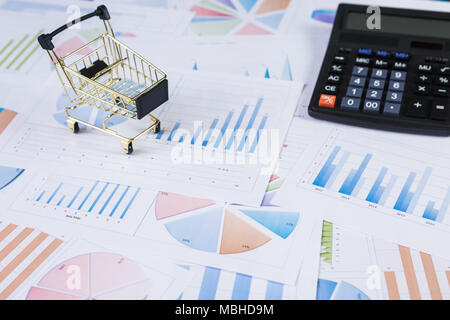 I carrelli della spesa con la calcolatrice sul grafici finanziari Foto Stock