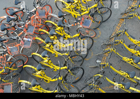 Righe di dockless noleggio biciclette parcheggiate su di una strada nella parte ovest di Pechino, Cina visto da sopra Foto Stock