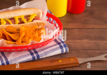 Hot Dog e patatine in un cesto di rosso su una tavola di legno Foto Stock