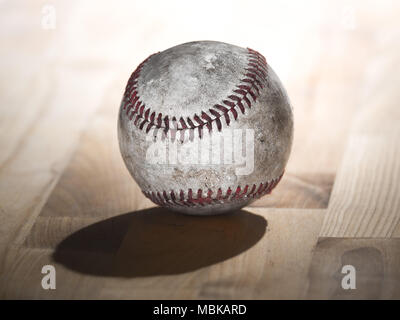 Close up sports immagine di sfondo di un vecchio usato weathered baseball in pelle che mostra gli intricati dettagli e lacci rossi seduto su legno butcher blocco alto Foto Stock