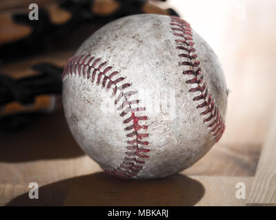 Close up sports immagine di sfondo di un vecchio usato weathered baseball cuoio recante nella parte anteriore di un guanto a sfera su un macellaio di legno contatore di blocchi. Foto Stock