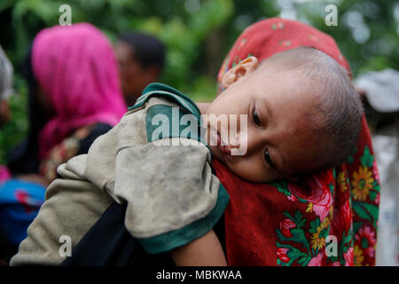 Un rifugiato Rohingya porta il suo bambino attraverso Palong Khali campo profughi a Ukhia In Cox bazar, Bangladesh Foto Stock