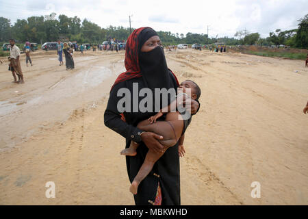 Un rifugiato Rohingya porta il suo bambino attraverso i punti di confine in Ukhia upazila di Cox's Bazar distretto, Bangladesh. Foto Stock