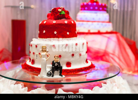 Figurine sul fondo del rosso e del bianco torta di nozze Foto Stock