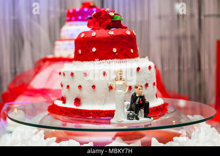 Figurine sul fondo del rosso e del bianco torta di nozze Foto Stock