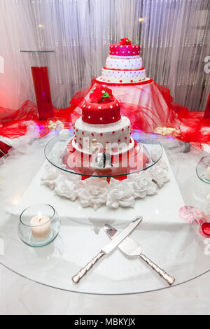 Figurine sul fondo del rosso e del bianco torta di nozze Foto Stock